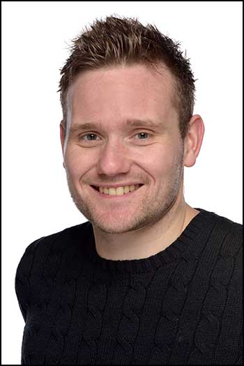 Portrait headshot photograph of actor in black jumper on a white background