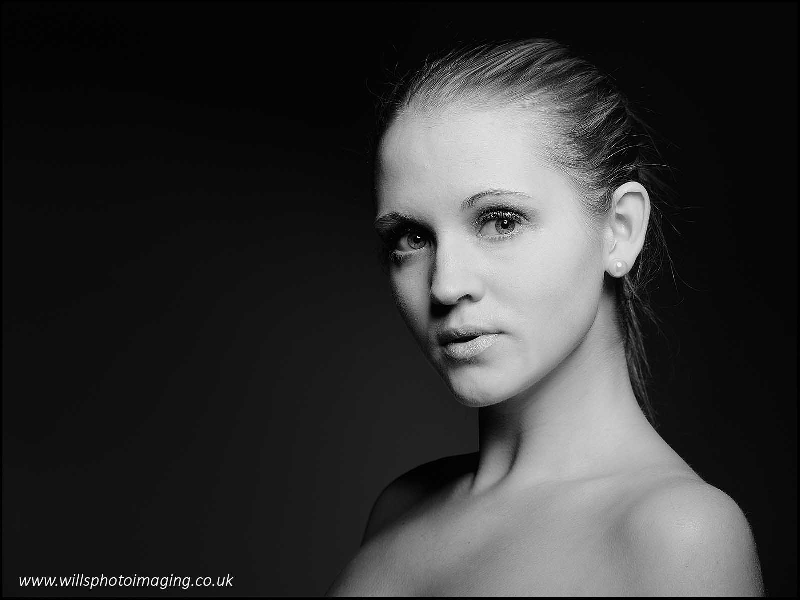 Classy and distinctive monochrome noir portrait photograph of a bare shouldered woman with a pearl earring
