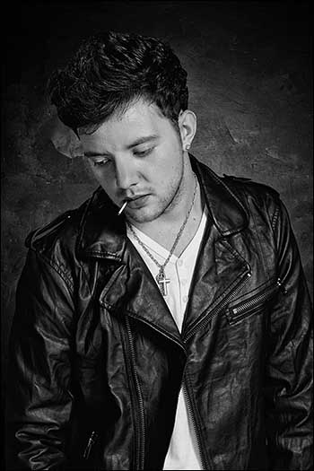 Styled monochrome portrait photograph of a man looking like a 1960s biker